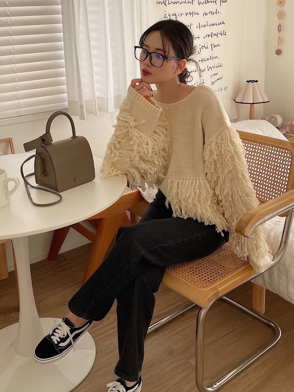 ホワイト系のニット/セーター、グレー系のショルダーバッグ、ブラック系のデニムパンツを着用したレディースの冬コーディネートの1枚目の写真