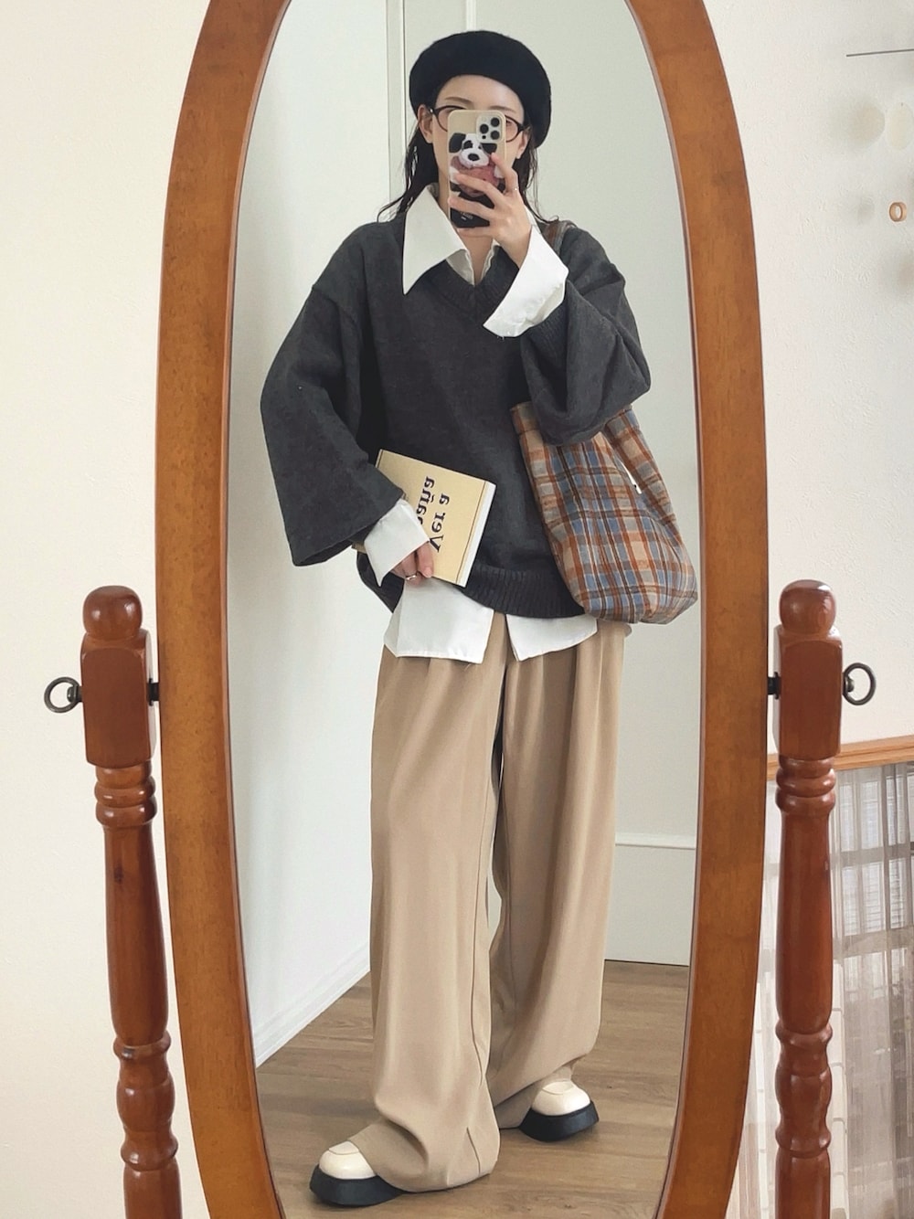 グレー系のニット/セーター、ホワイト系のシャツ/ブラウス、ベージュ系のパンツを着用したレディースの秋コーディネートの1枚目の写真