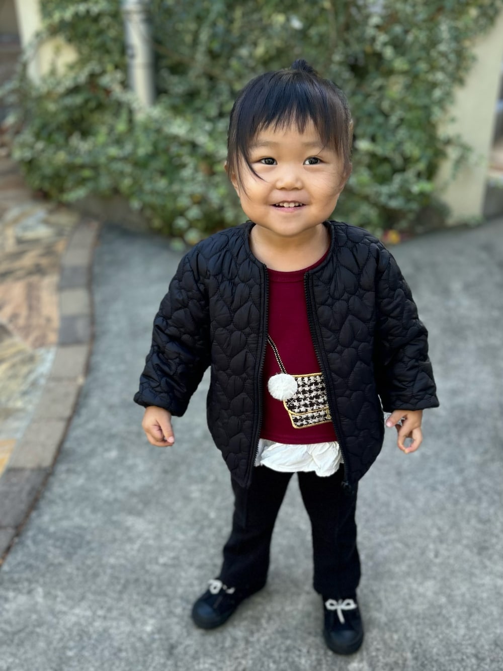 ブラック系のノーカラージャケット、レッド系のチュニック、ブラック系のパンツを着用したキッズの冬コーディネートの1枚目の写真