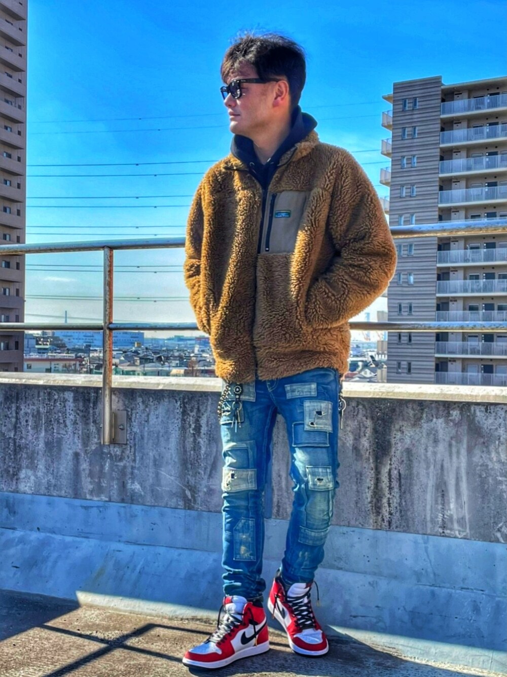 ベージュ系のブルゾン、ブルー系のデニムパンツ、ブラック系のパーカーを着用したメンズの冬コーディネートの2枚目の写真