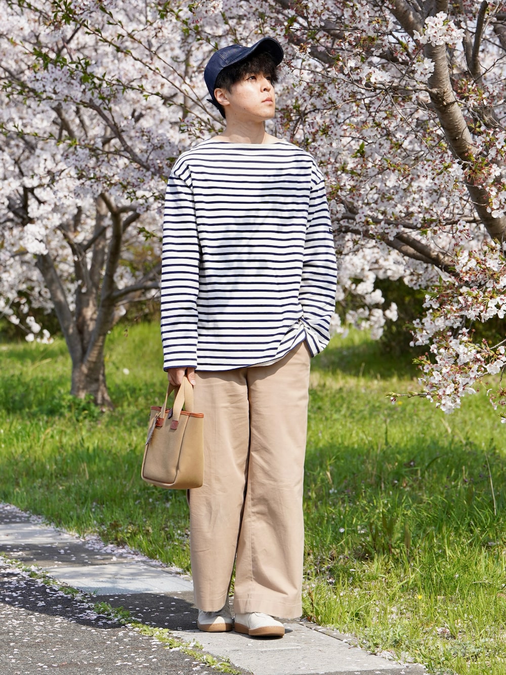 ブルー系のTシャツ/カットソー、ベージュ系のトートバッグ、ブラウン系のスニーカーを着用したメンズの春コーディネートの1枚目の写真