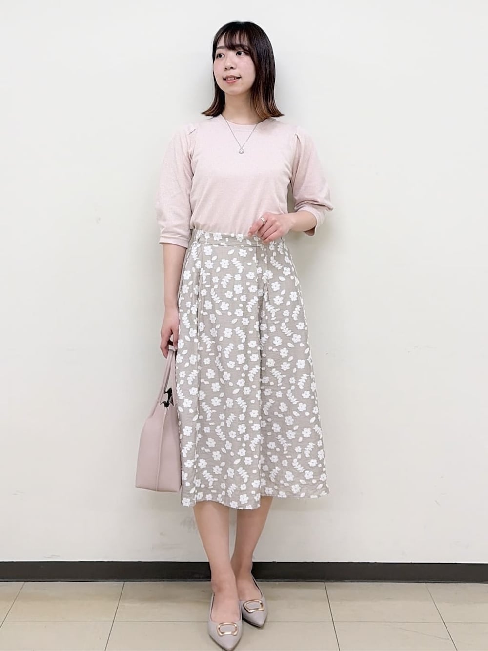 ベージュ系のパンプス、ベージュ系のスカート、ピンク系のニット/セーターを着用したレディースの春コーディネートの1枚目の写真