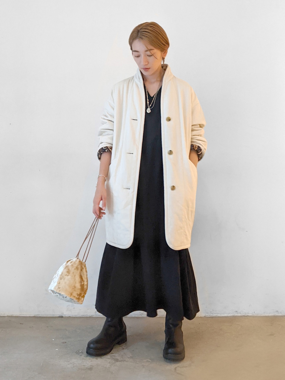 ホワイト系のブルゾン、ブラック系のブーツを着用したレディースの秋コーディネートの1枚目の写真