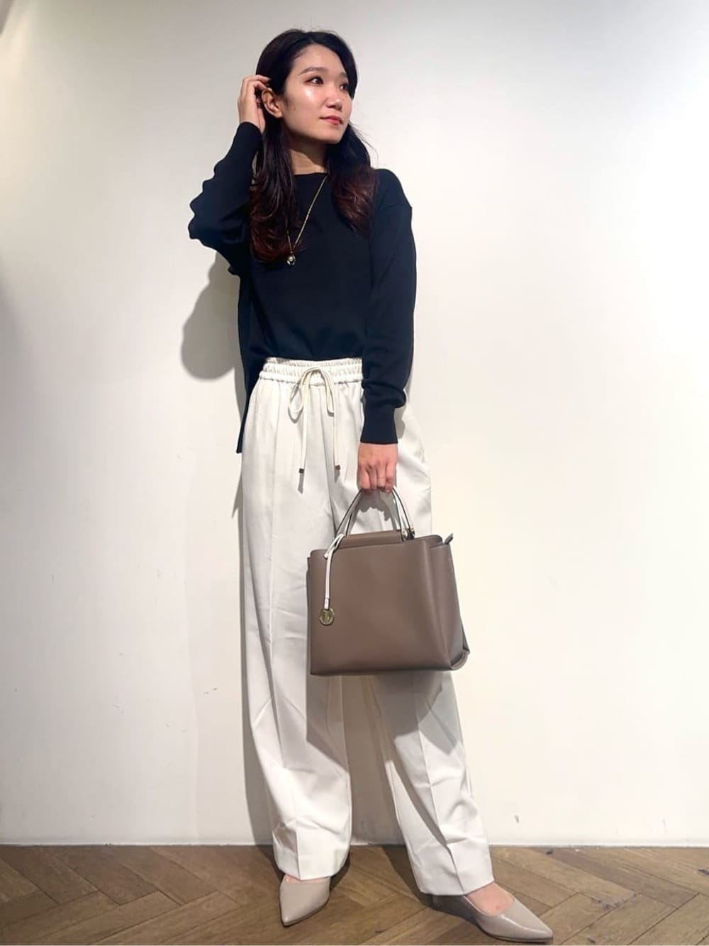 ブラック系のニット/セーター、ホワイト系のその他パンツ、ベージュ系のトートバッグを着用したレディースの秋コーディネートの1枚目の写真