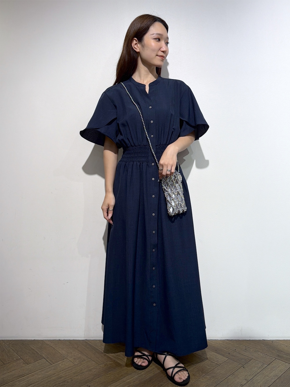 ブルー系のワンピース、シルバー系のショルダーバッグ、ブラック系のサンダルを着用したレディースの夏コーディネートの1枚目の写真