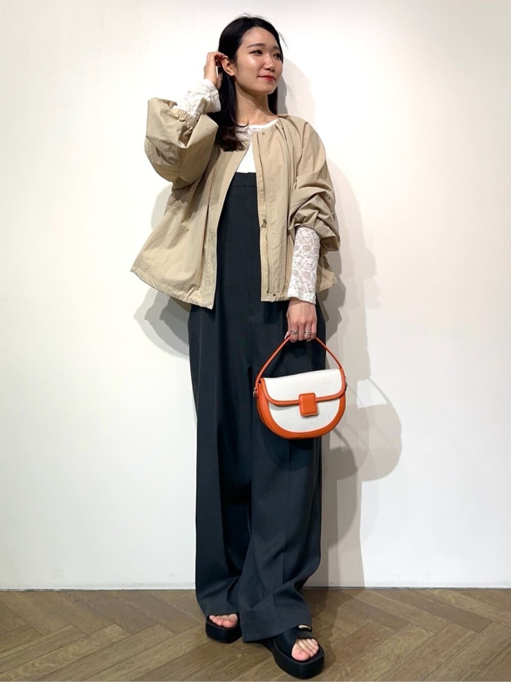 ベージュ系のノーカラーコート、ホワイト系のTシャツ/カットソー、グレー系のサロペット/オーバーオールを着用したレディースの春コーディネートの1枚目の写真