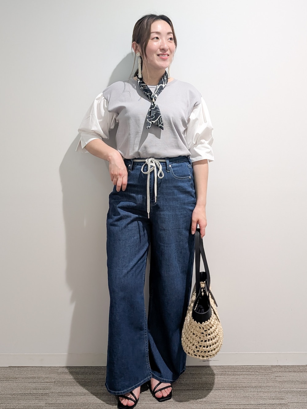 グレー系のニット/セーター、ブルー系のデニムパンツ、ブラック系のトートバッグを着用したレディースの夏コーディネートの1枚目の写真