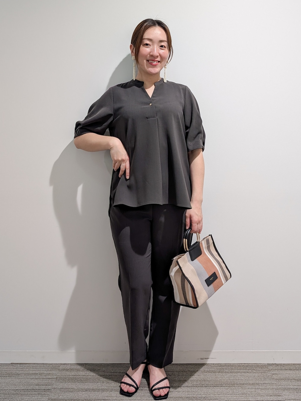 グレー系のシャツ/ブラウス、グレー系のその他パンツ、ブラック系のトートバッグを着用したレディースの春コーディネートの1枚目の写真