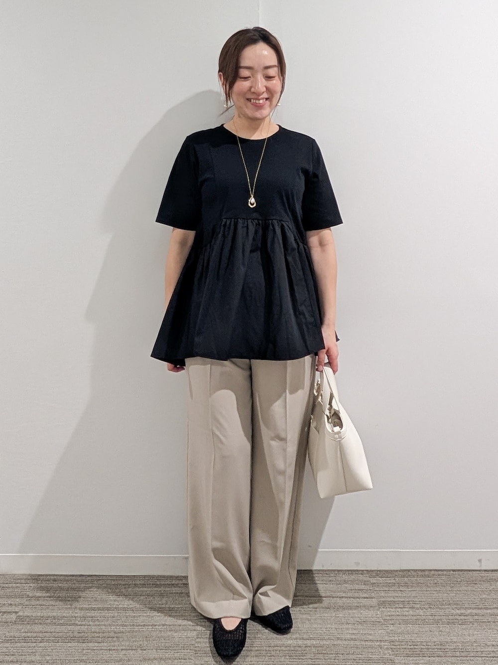 ブラック系のTシャツ/カットソー、ベージュ系のその他パンツ、ホワイト系のショルダーバッグを着用したレディースの春コーディネートの1枚目の写真