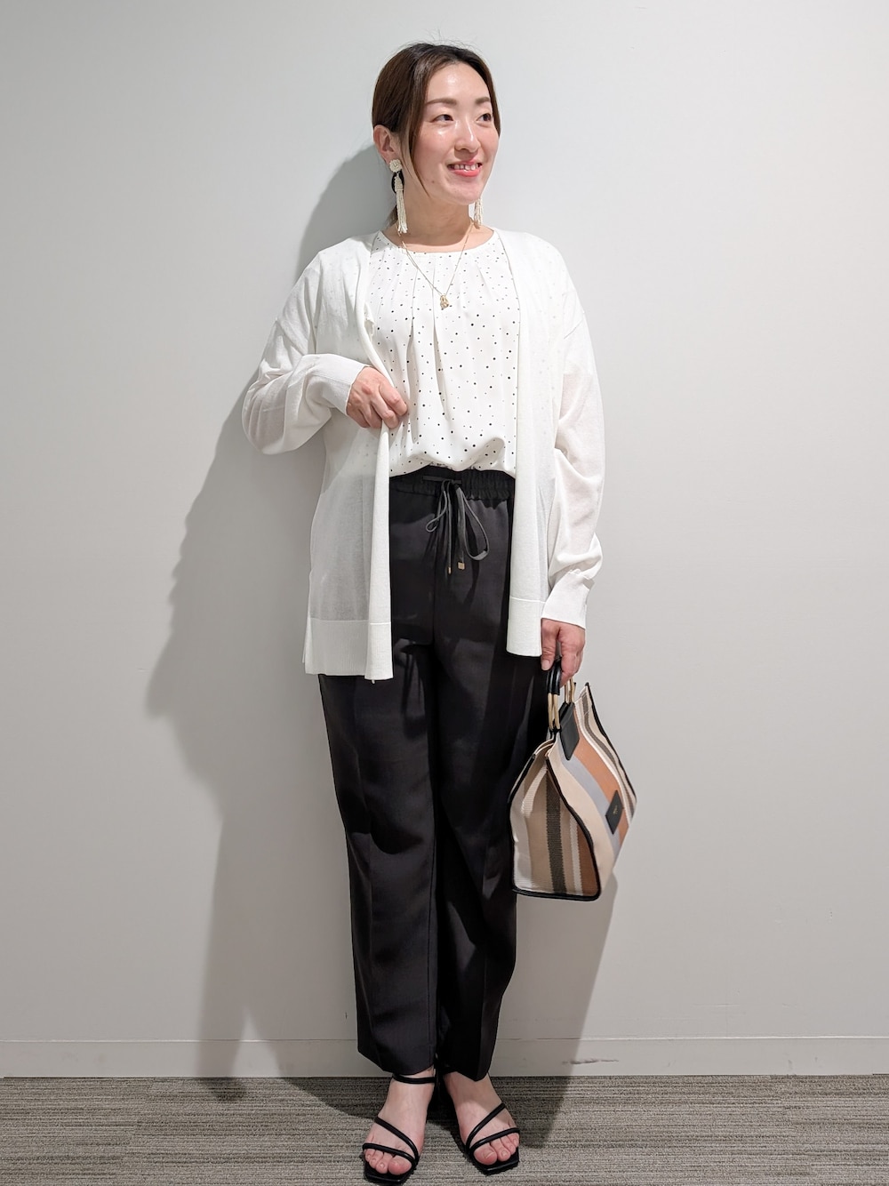 ホワイト系のシャツ/ブラウス、グレー系のその他パンツ、ブラック系のサンダルを着用したレディースの春コーディネートの1枚目の写真