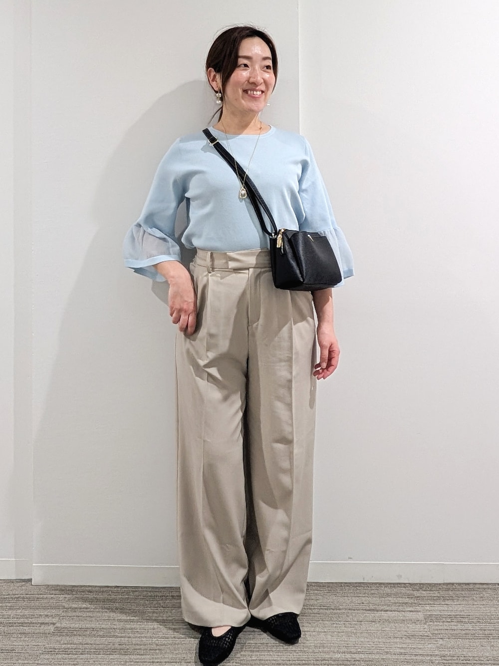 ブルー系のニット/セーター、ベージュ系のその他パンツ、ブラック系のショルダーバッグを着用したレディースの春コーディネートの1枚目の写真