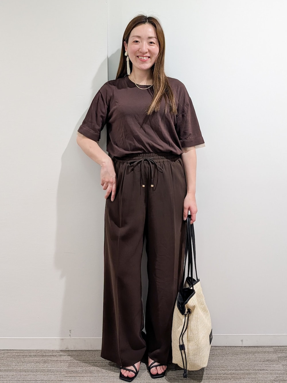 ブラウン系のニット/セーター、ブラウン系のその他パンツ、ホワイト系のトートバッグを着用したレディースの夏コーディネートの1枚目の写真