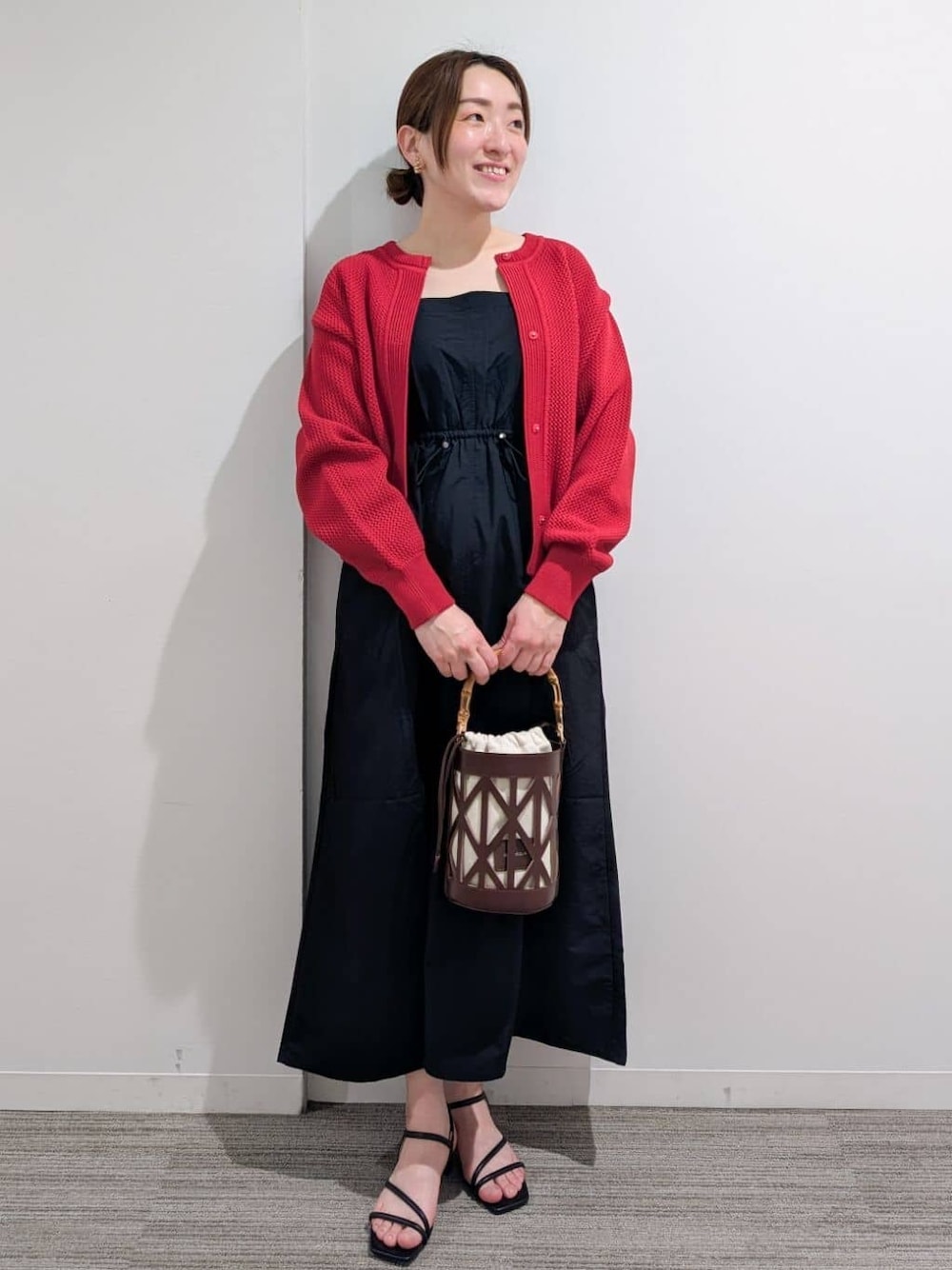 ブラック系のワンピース、レッド系のカーディガン/ボレロ、ブラック系のサンダルを着用したレディースの春コーディネートの1枚目の写真
