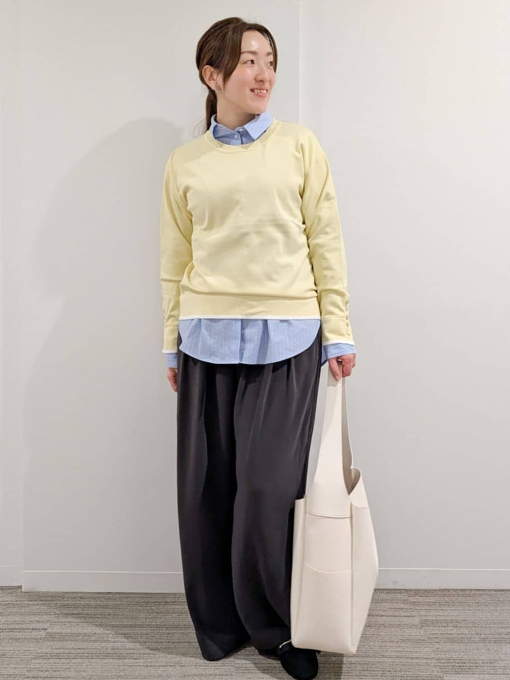 イエロー系のニット/セーター、ブルー系のシャツ/ブラウス、グレー系のその他パンツを着用したレディースの冬コーディネートの1枚目の写真