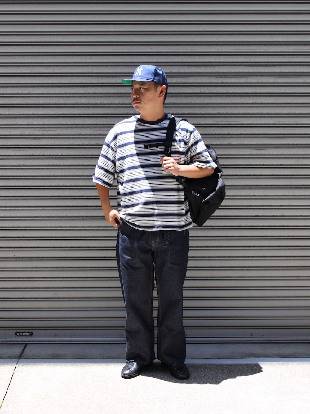 ブルー系のデニムパンツ、ブルー系のTシャツ/カットソー、ブラック系のバックパック/リュックを着用したメンズの夏コーディネートの1枚目の写真