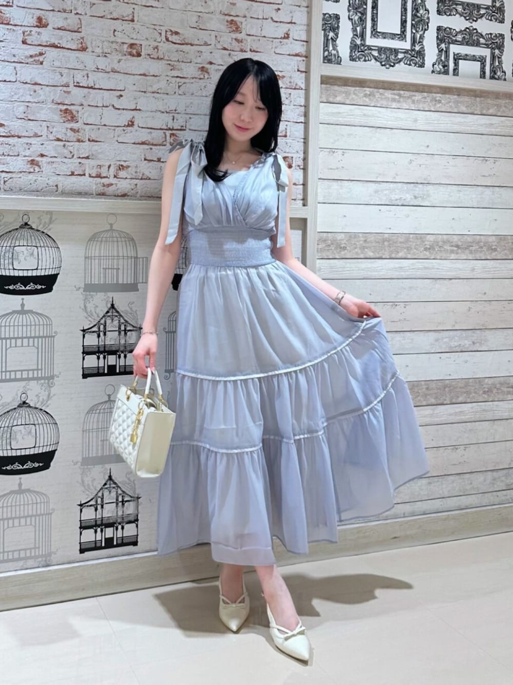 ブルー系のワンピース、ホワイト系のハンドバッグ、ホワイト系のパンプスを着用したレディースの夏コーディネートの1枚目の写真