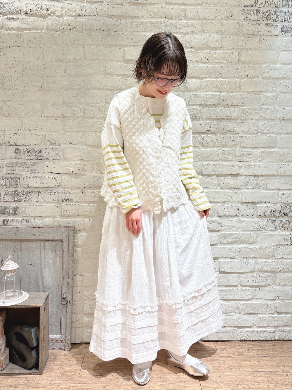 イエロー系のTシャツ/カットソー、ホワイト系のベスト、ホワイト系のスカートを着用したレディースの春コーディネートの1枚目の写真