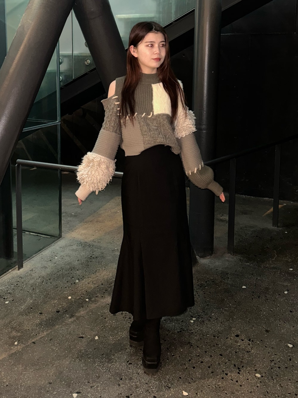 ブラウン系のニット/セーター、ブラック系のスカート、ブラック系のブーツを着用したレディースの冬コーディネートの1枚目の写真