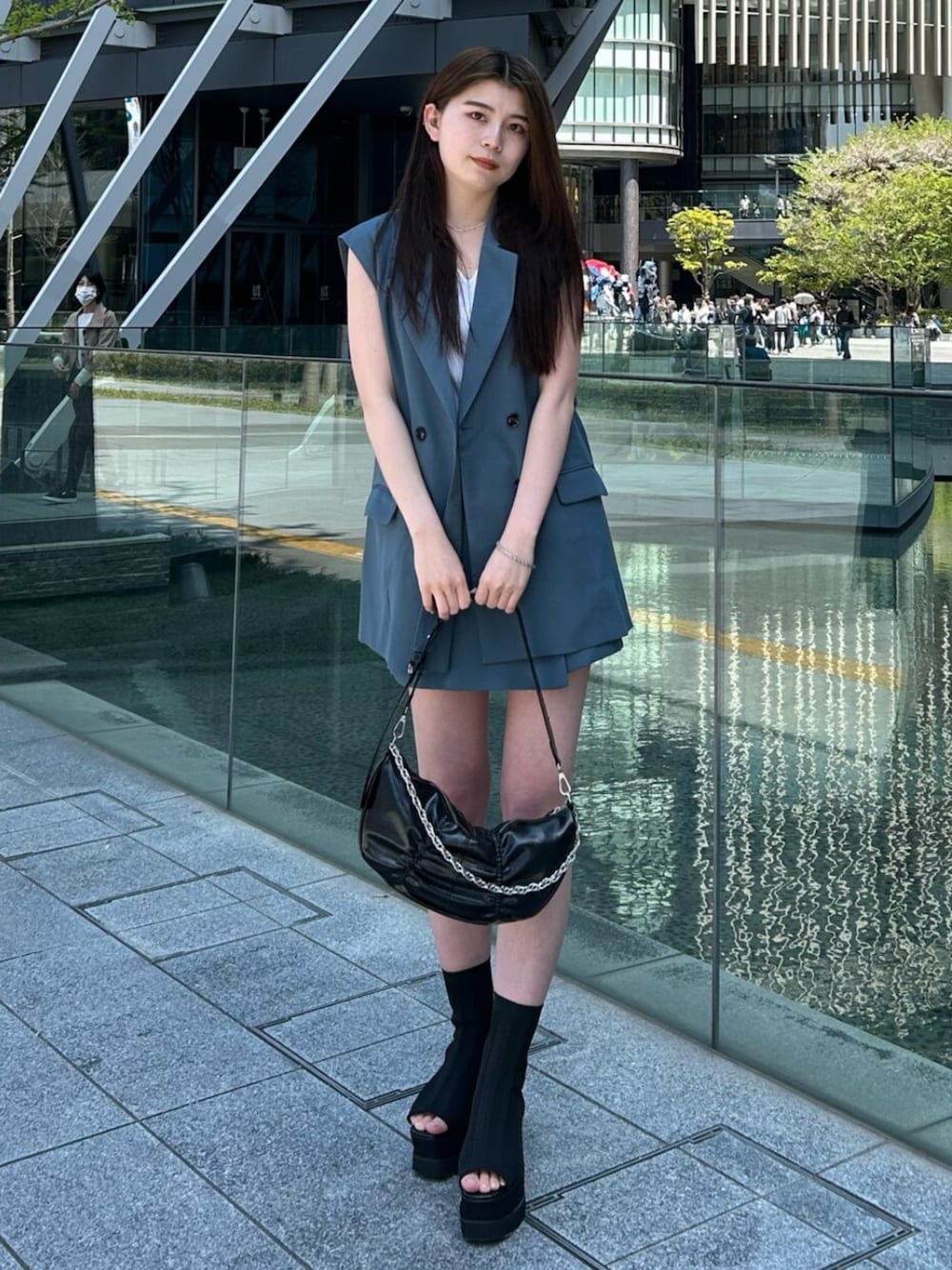 ブルー系のベスト、ブルー系のスカート、ホワイト系のタンクトップを着用したレディースの春コーディネートの1枚目の写真