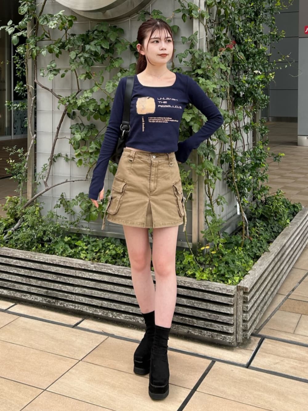 ブラック系のブーツ、ブルー系のTシャツ/カットソー、ベージュ系のスカートを着用したレディースの秋コーディネートの1枚目の写真