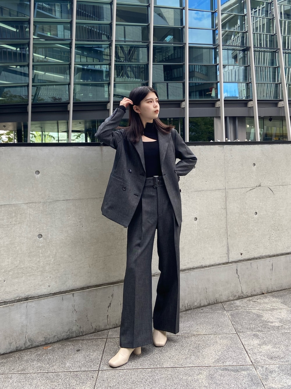 グレー系のテーラードジャケット、ブラック系のニット/セーター、グレー系のスラックスを着用したレディースの秋コーディネートの1枚目の写真