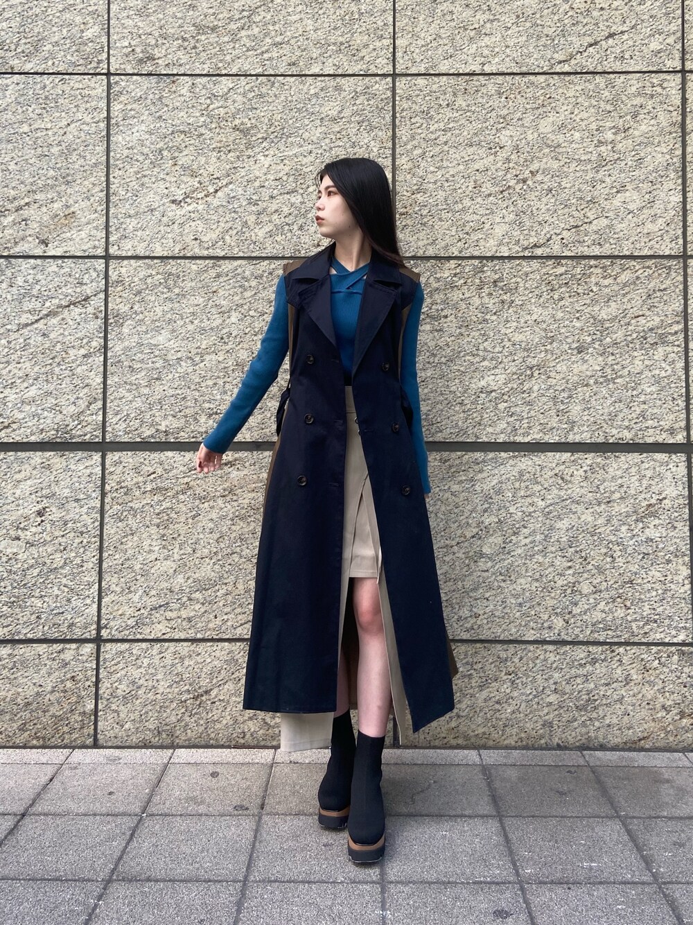 ブルー系のトレンチコート、ホワイト系のスカート、ブラック系のブーツを着用したレディースの秋コーディネートの1枚目の写真