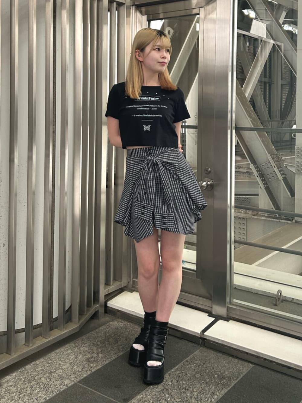 ブラック系のブーツ、ブルー系のスカート、ブラック系のTシャツ/カットソーを着用したレディースの夏コーディネートの1枚目の写真