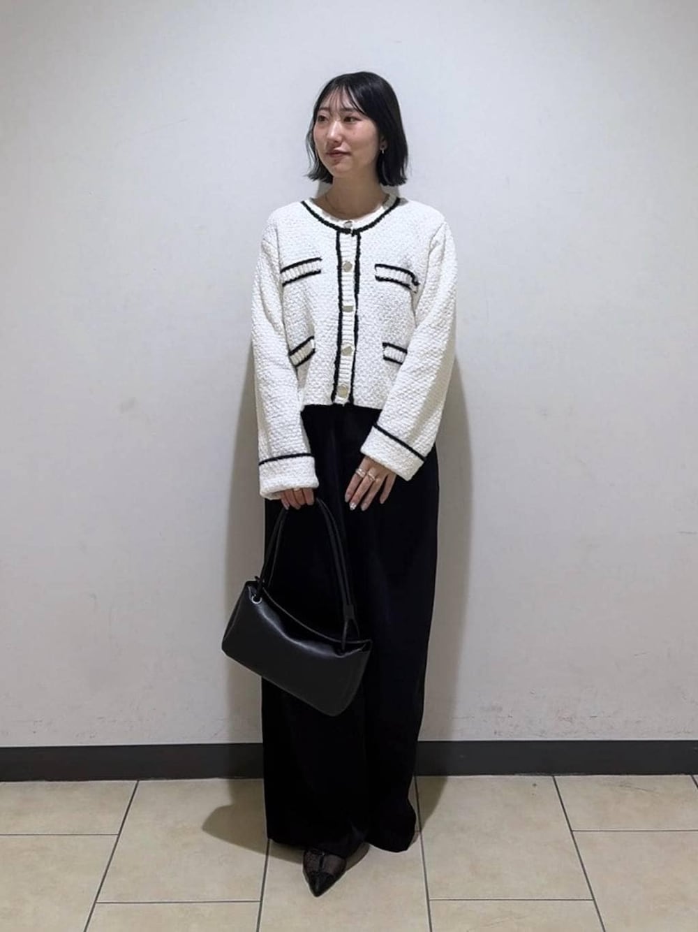 ブラック系のスラックス、ホワイト系のカーディガン/ボレロ、ブラック系のパンプスを着用したレディースの冬コーディネートの1枚目の写真