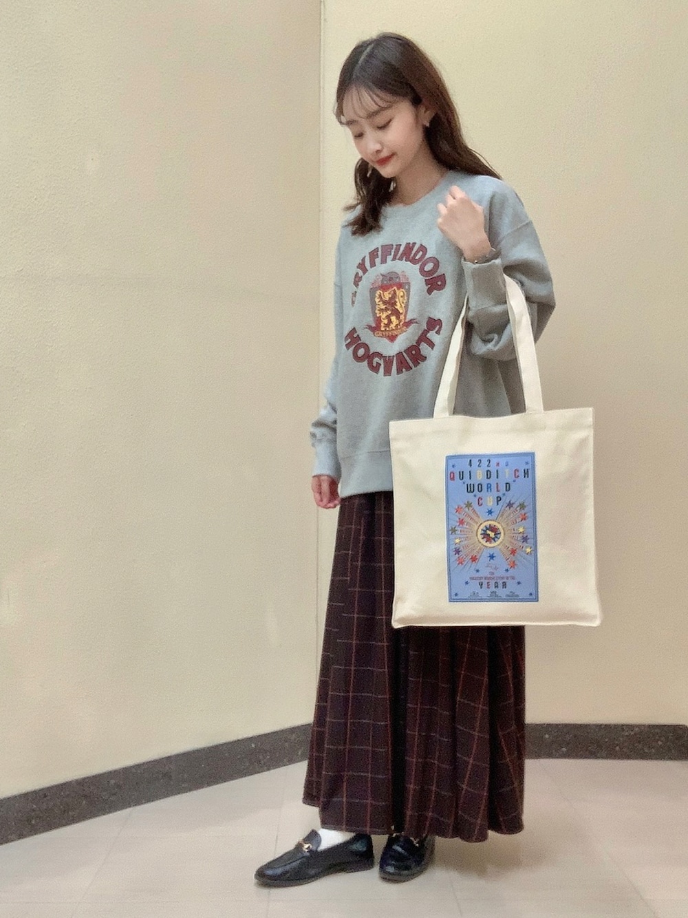 グレー系のスウェット、ホワイト系のトートバッグ、ブラウン系のスカートを着用したレディースの冬コーディネートの1枚目の写真