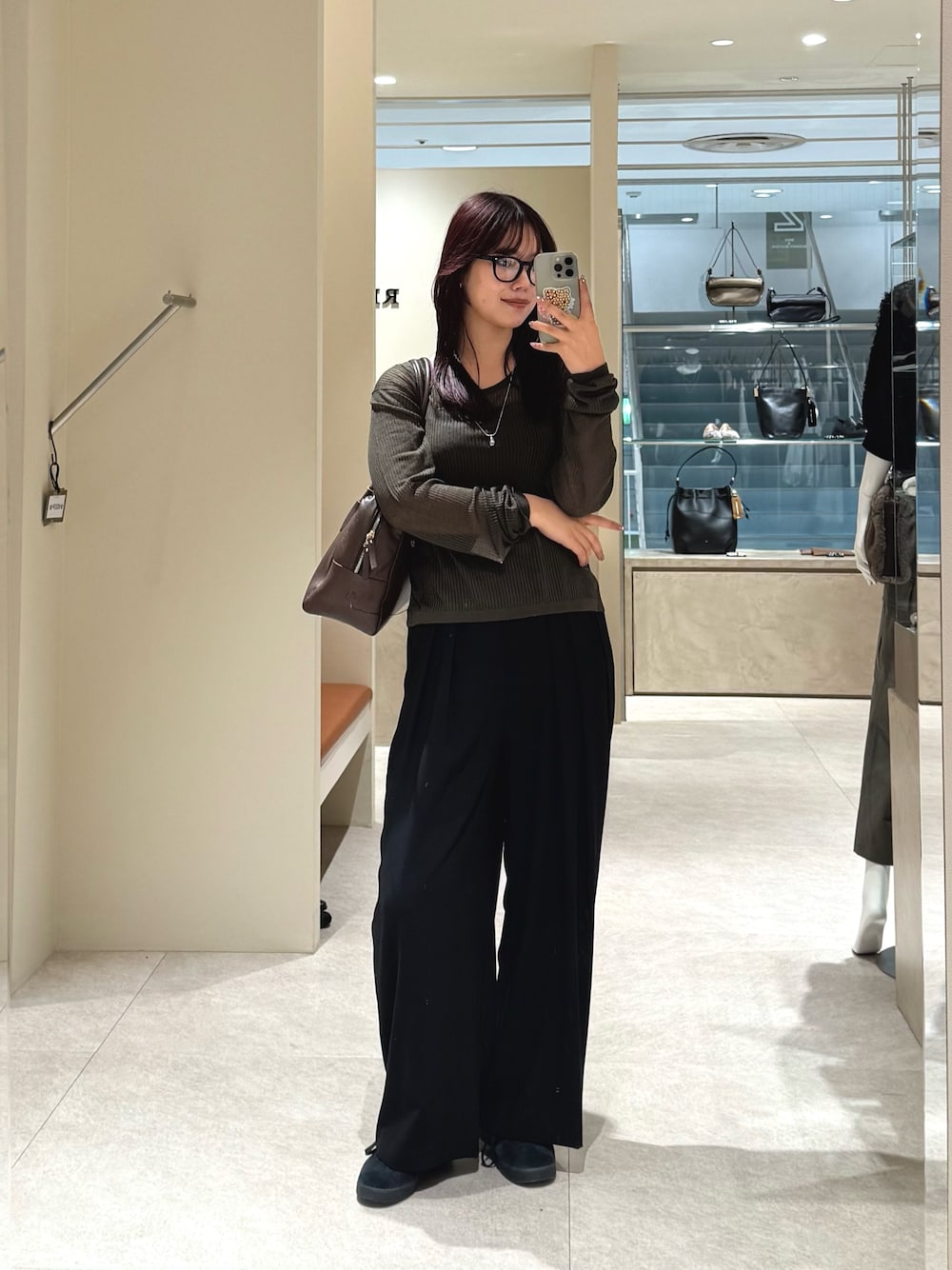 グリーン系のニット/セーター、ブラック系のスラックス、ブラウン系のボストンバッグを着用したレディースの秋コーディネートの1枚目の写真