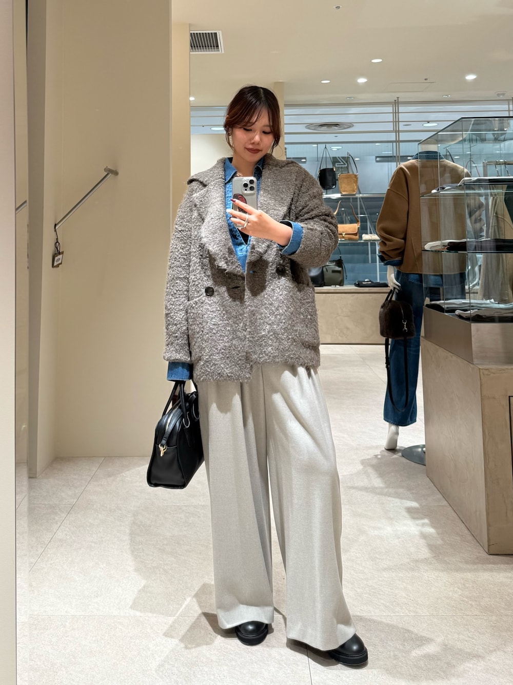 ブラウン系のその他アウター、ブルー系のシャツ/ブラウス、ブラック系のボストンバッグを着用したレディースの秋コーディネートの1枚目の写真