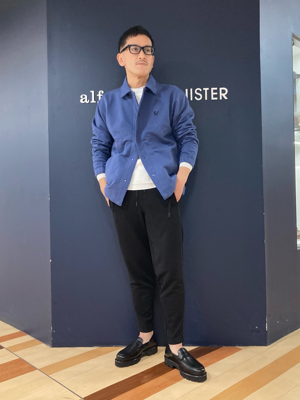 ブルー系のブルゾン、ブラック系のスラックス、ブラック系のローファーを着用したメンズの春コーディネートの1枚目の写真