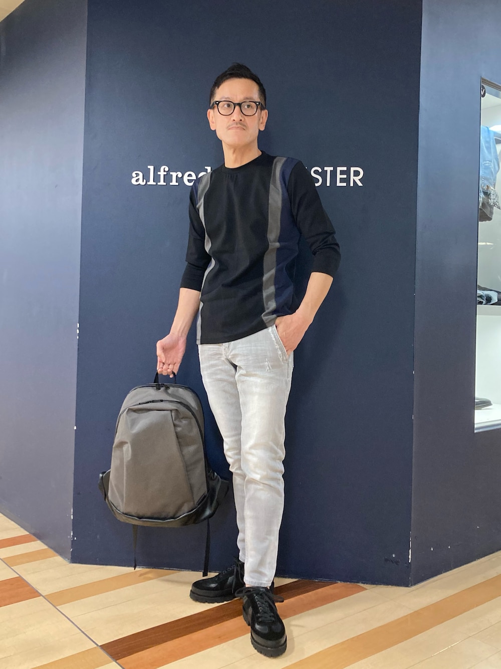 ブラック系のTシャツ/カットソー、グレー系のデニムパンツ、グレー系のバックパック/リュックを着用したメンズの春コーディネートの1枚目の写真