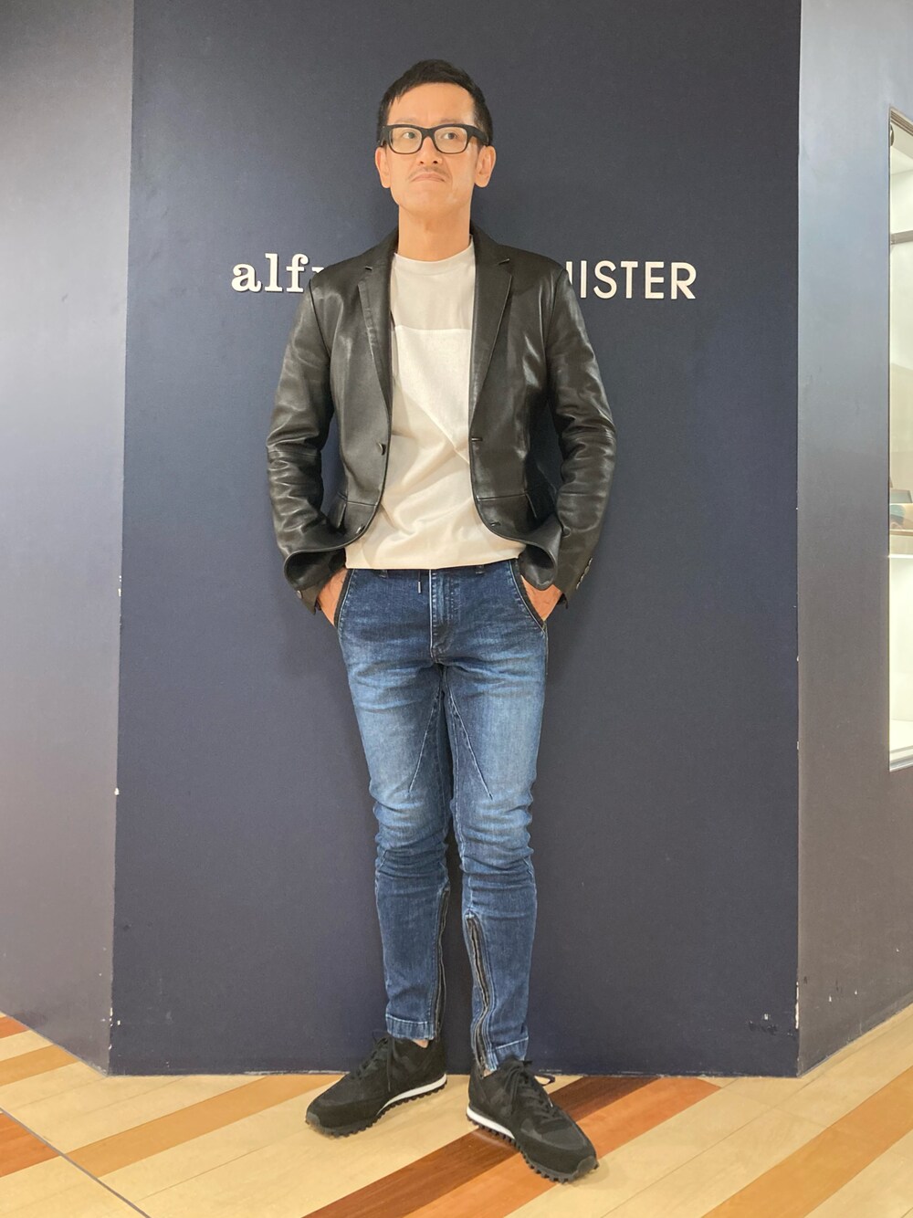 ブラック系のテーラードジャケット、ブルー系のデニムパンツ、ブラック系のスニーカーを着用したメンズの夏コーディネートの1枚目の写真