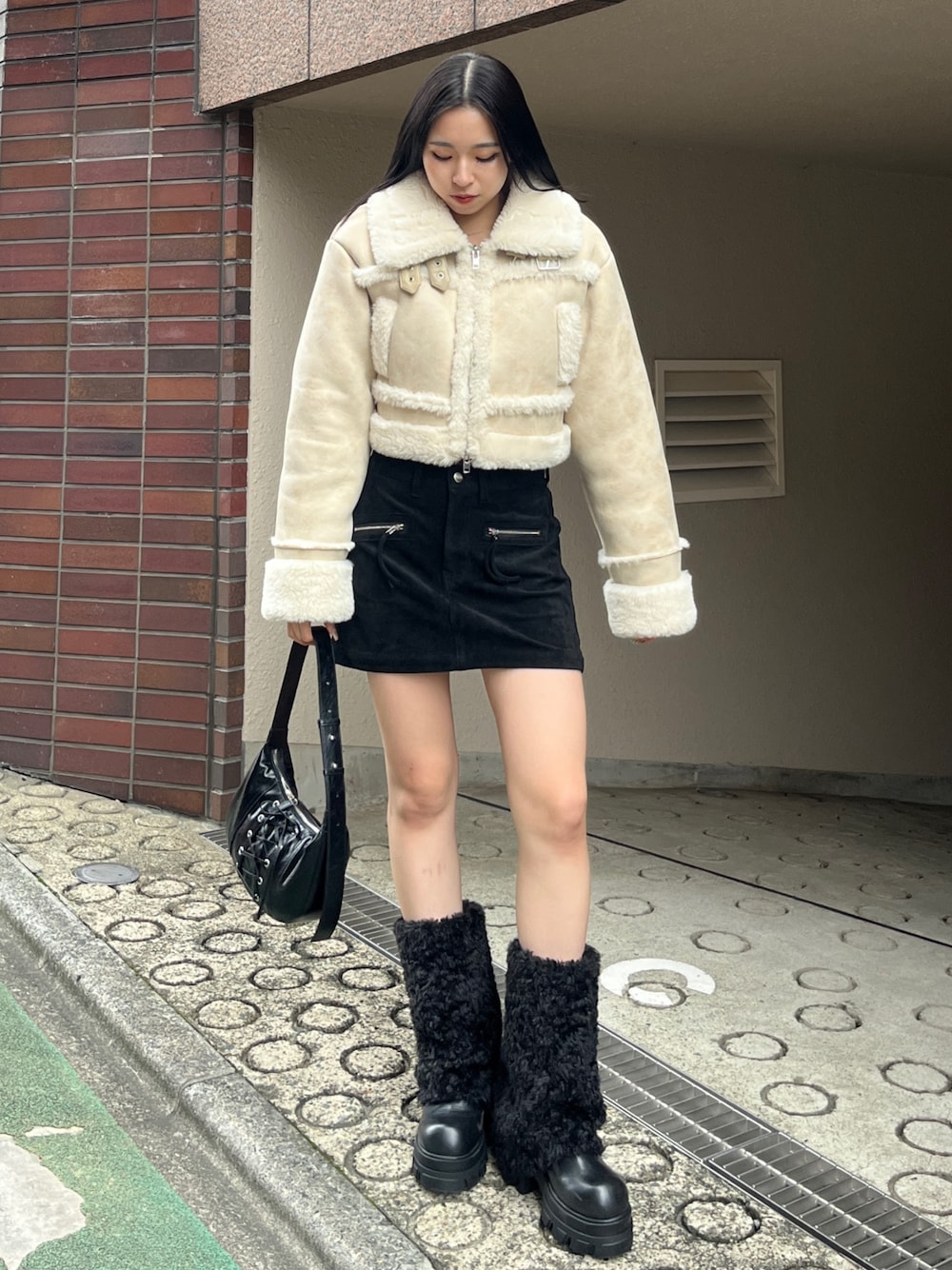 ブラック系のブーツ、ホワイト系のブルゾン、ブラック系のスカートを着用したレディースの冬コーディネートの1枚目の写真