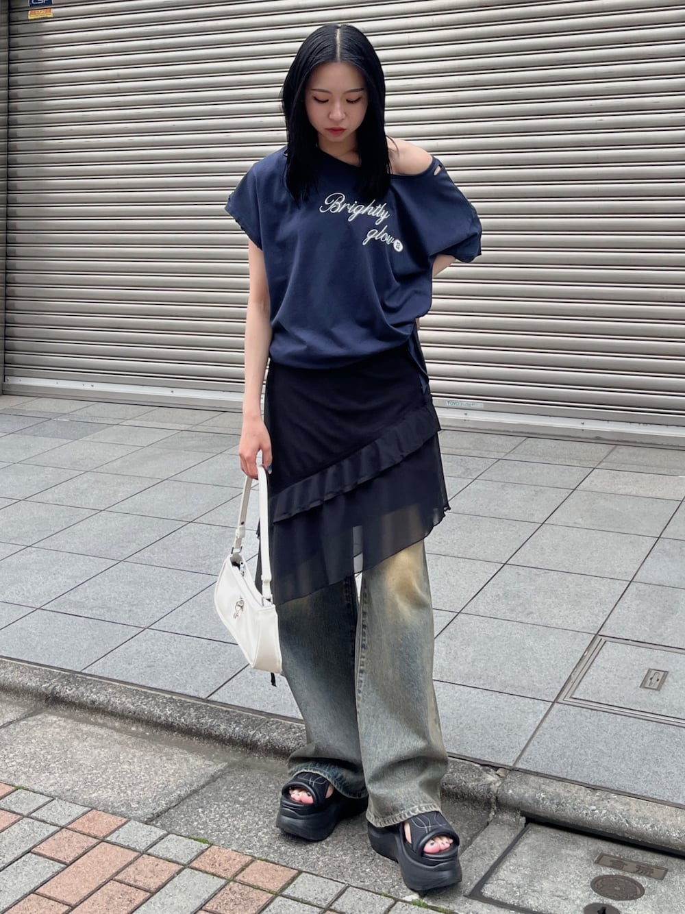 ブルー系のTシャツ/カットソー、ブラック系のスカート、ブルー系のデニムパンツを着用したレディースの春コーディネートの1枚目の写真