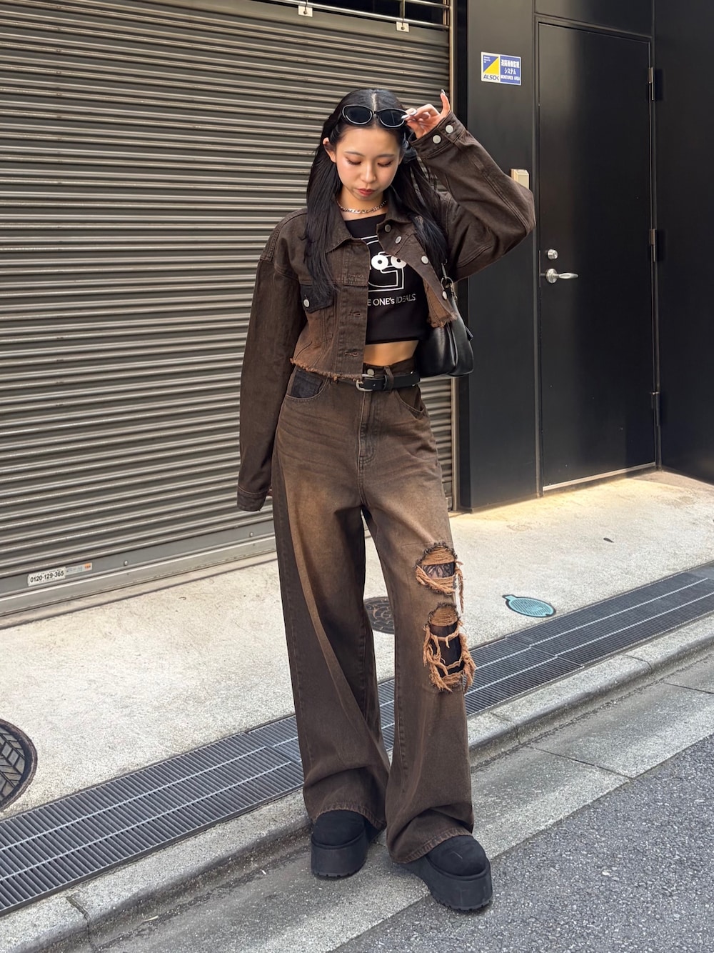 ブラック系のTシャツ/カットソー、ブラウン系のデニムパンツ、ブラック系のハンドバッグを着用したレディースの秋コーディネートの1枚目の写真