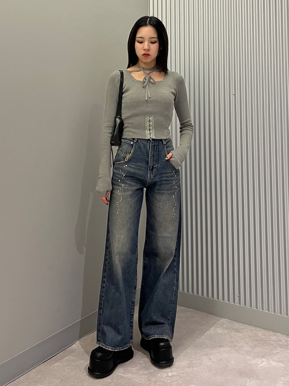 グレー系のニット/セーター、ブルー系のデニムパンツ、ブラック系のショルダーバッグを着用したレディースの秋コーディネートの1枚目の写真