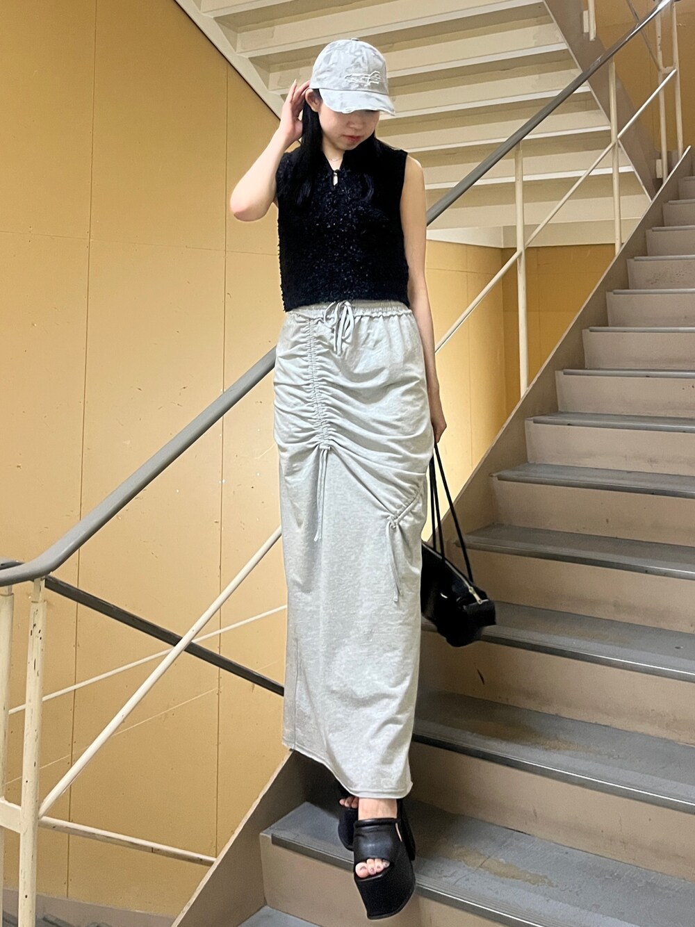 ブラック系のニット/セーター、グレー系のスカート、ブラック系のサンダルを着用したレディースの夏コーディネートの1枚目の写真