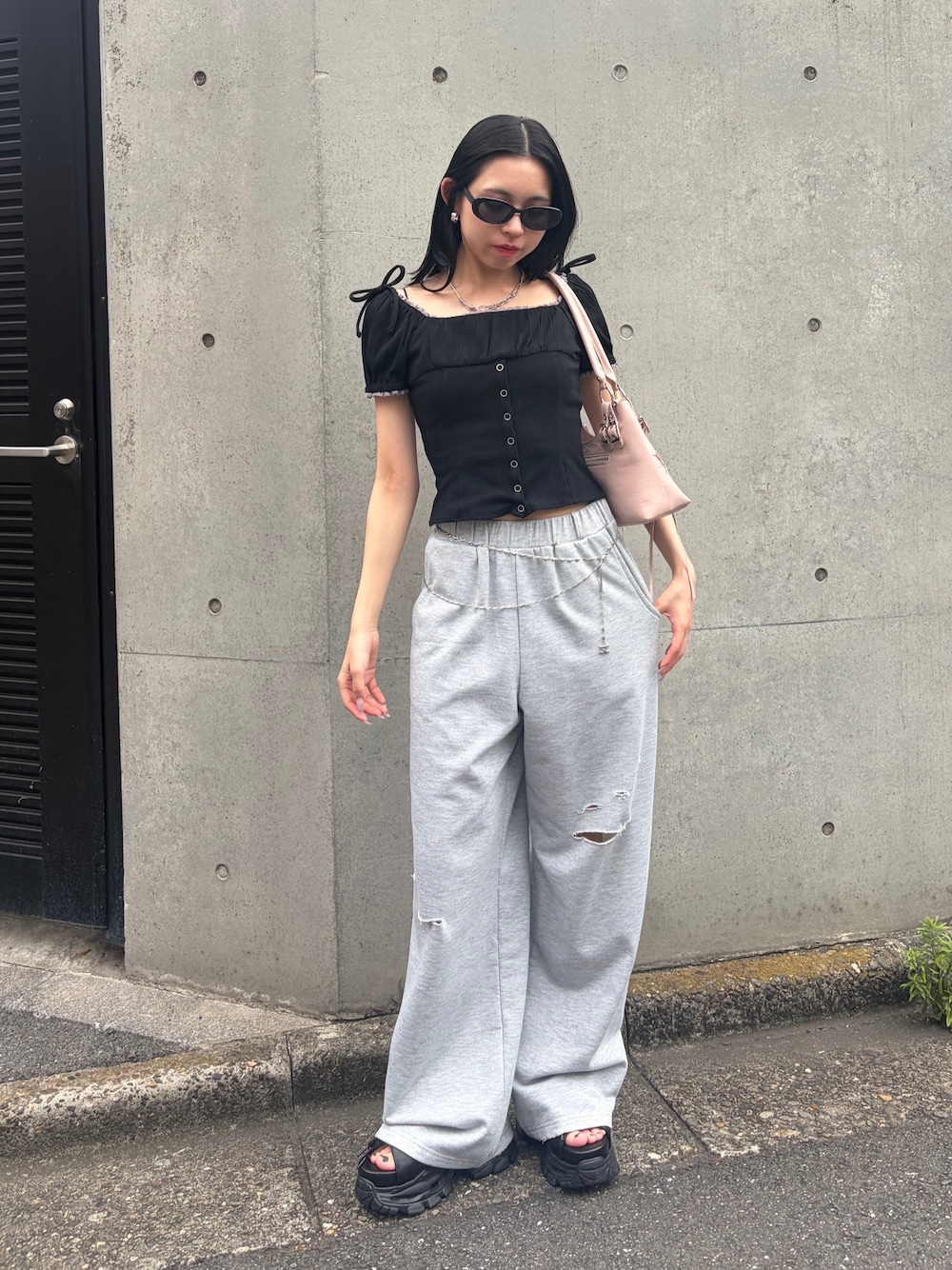 グレー系のスウェットパンツ、ブラック系のTシャツ/カットソー、ピンク系のショルダーバッグを着用したレディースの夏コーディネートの1枚目の写真