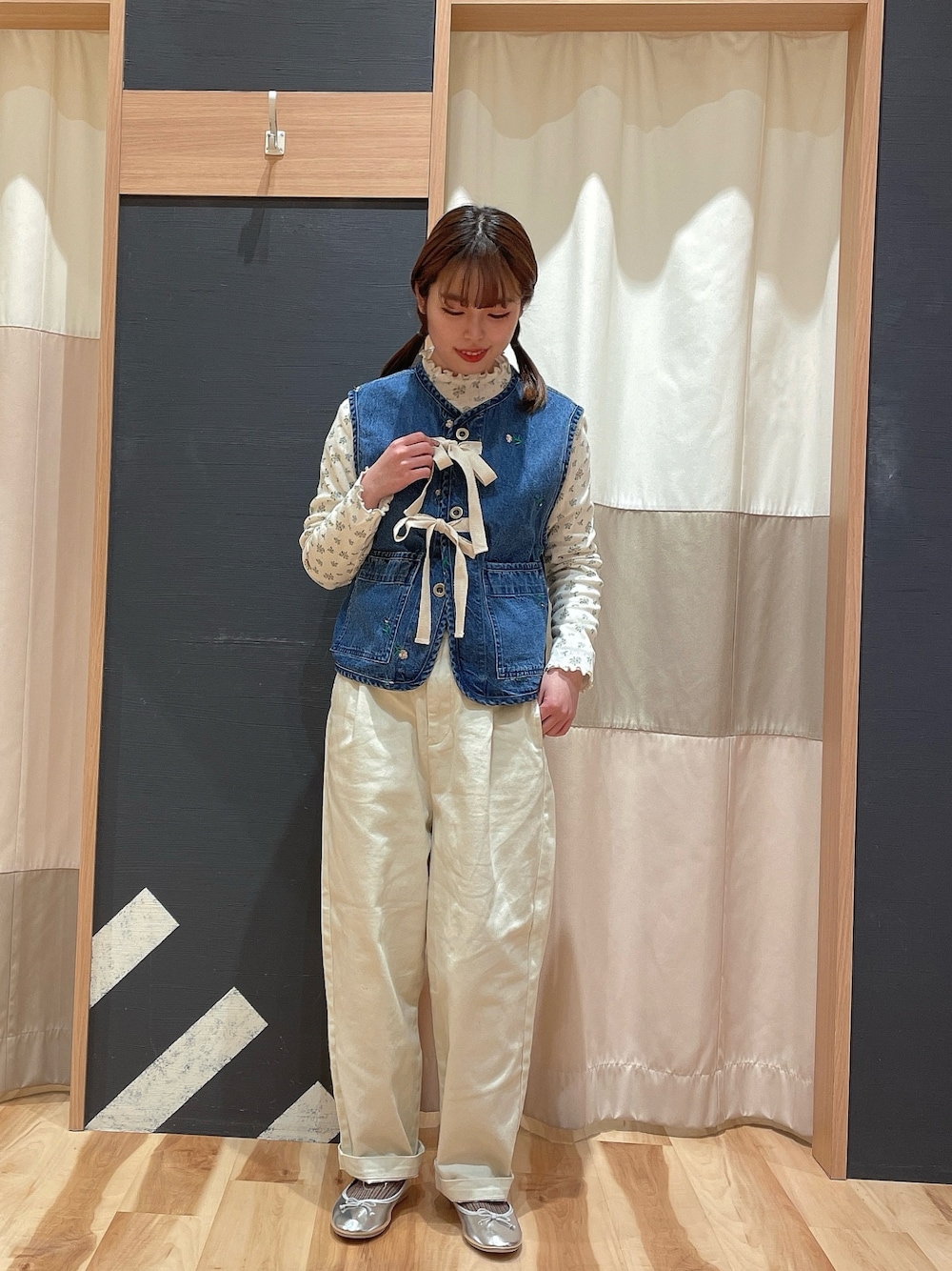 ブルー系のベスト、ホワイト系のデニムパンツを着用したレディースの冬コーディネートの1枚目の写真