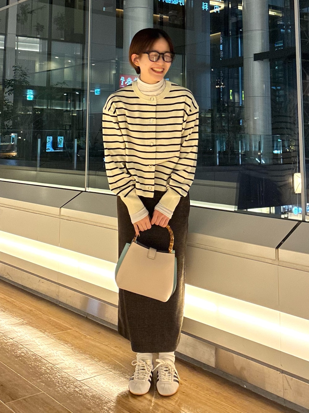 ホワイト系のカーディガン/ボレロ、グリーン系のTシャツ/カットソー、ブラウン系のスカートを着用したレディースの秋コーディネートの1枚目の写真