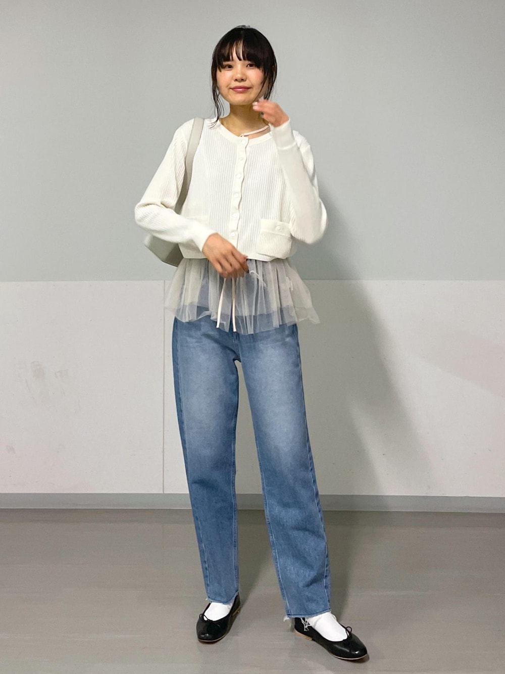 ブラック系のバレエシューズ、ホワイト系のカーディガン/ボレロ、ブルー系のデニムパンツを着用したレディースの秋コーディネートの1枚目の写真