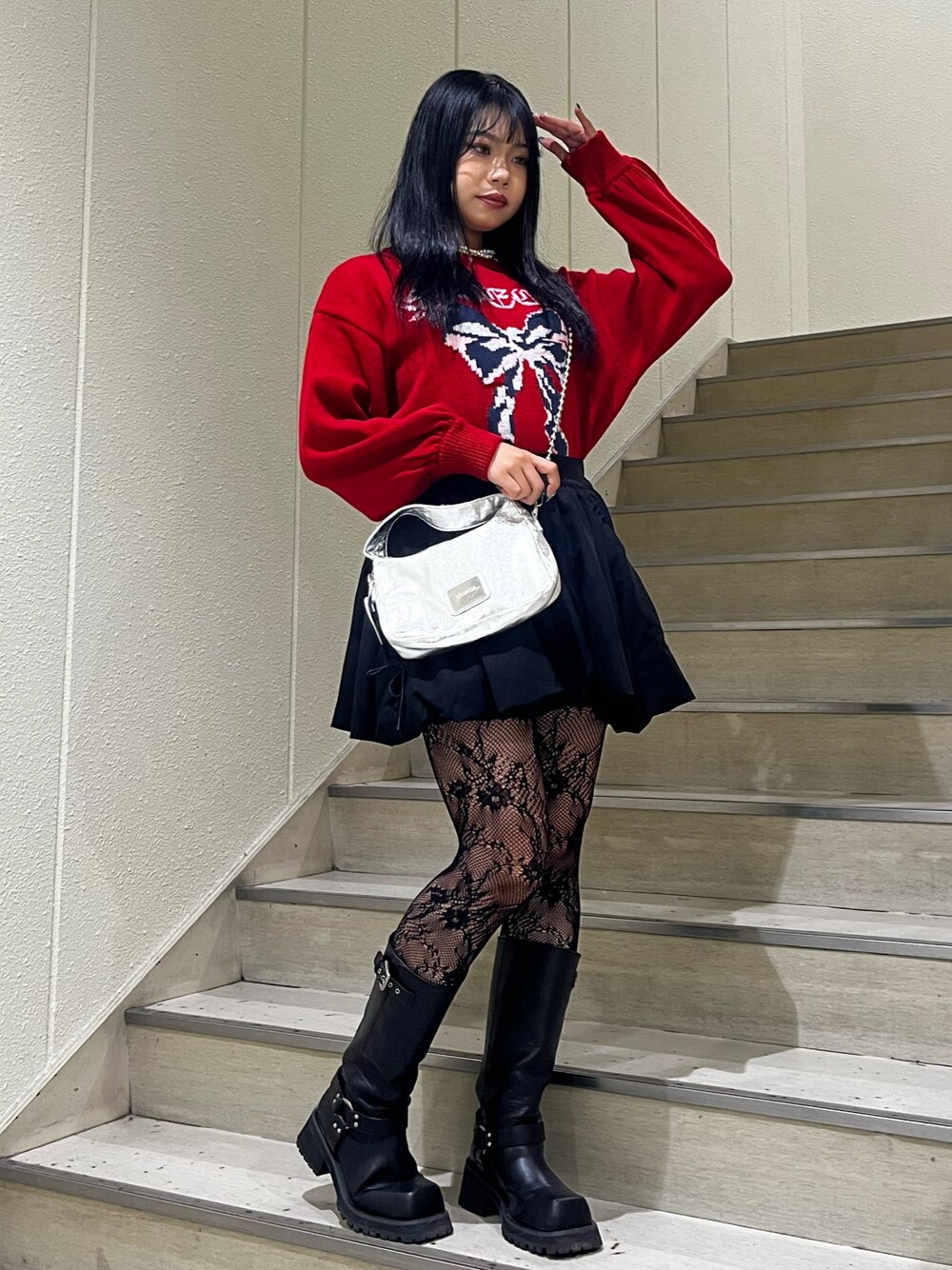 シルバー系のハンドバッグ、ブラック系のスカート、ブラック系のブーツを着用したレディースの冬コーディネートの1枚目の写真