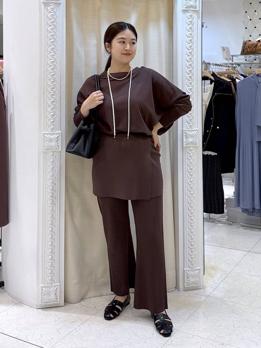 ブラック系のハンドバッグ、ブラック系のパンプス、ブラウン系のその他パンツを着用したレディースの春コーディネートの1枚目の写真