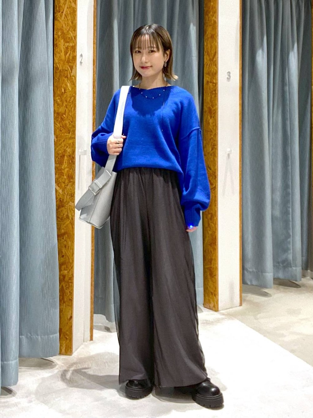 ブルー系のニット/セーター、ブラック系のブーツ、シルバー系のショルダーバッグを着用したレディースの秋コーディネートの1枚目の写真