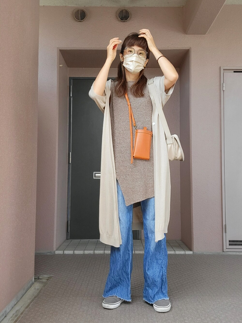 ブルー系のデニムパンツ、グレー系のスニーカー、ブラウン系のニット/セーターを着用したレディースの秋コーディネートの1枚目の写真