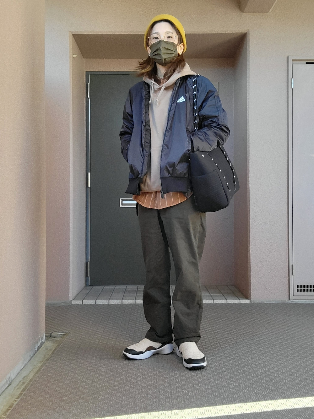 グリーン系のチノパンツ、ベージュ系のスリッポン、ブラック系のその他アウターを着用したレディースの冬コーディネートの2枚目の写真