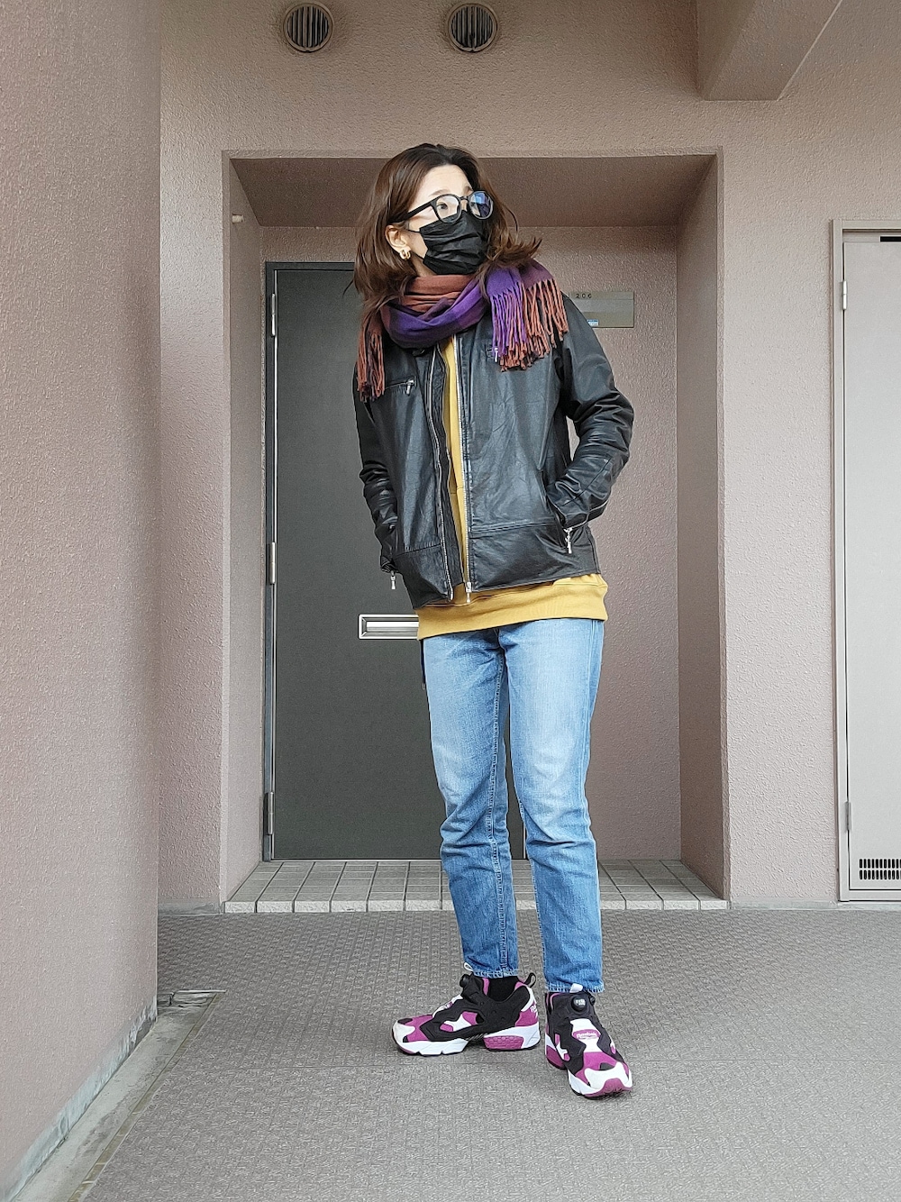 ブラック系のライダースジャケット、ブルー系のデニムパンツ、パープル系のスニーカーを着用したレディースの冬コーディネートの3枚目の写真