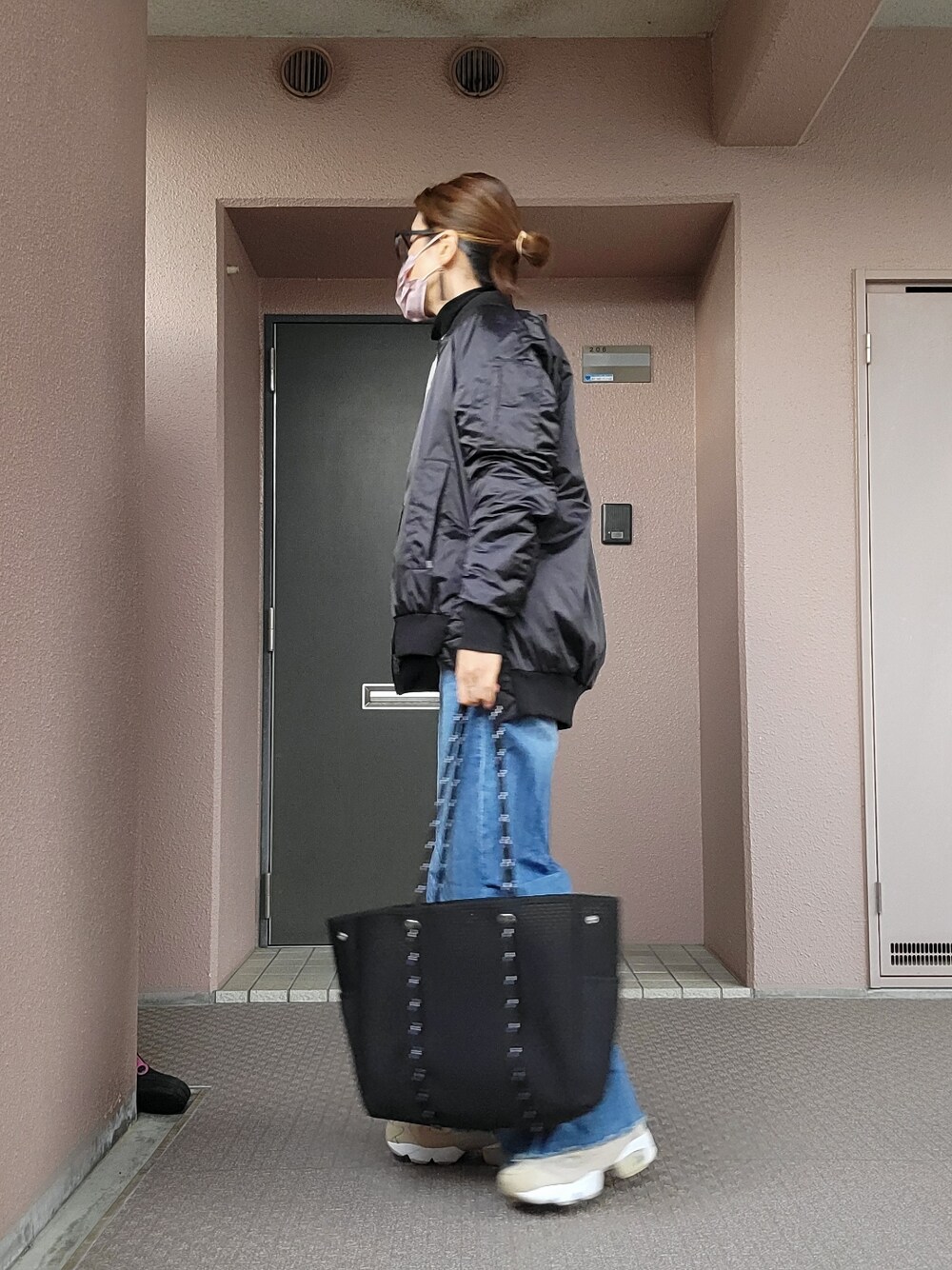 ブルー系のデニムパンツ、ベージュ系のスニーカー、ブラック系のトートバッグを着用したレディースの冬コーディネートの2枚目の写真